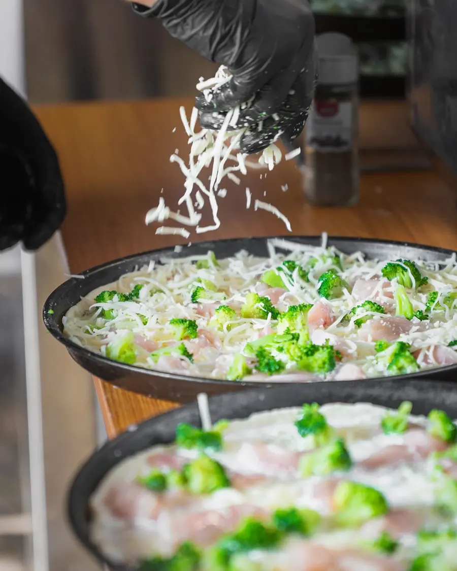Käse wird über die Brokkoli-Pizzen gestreut