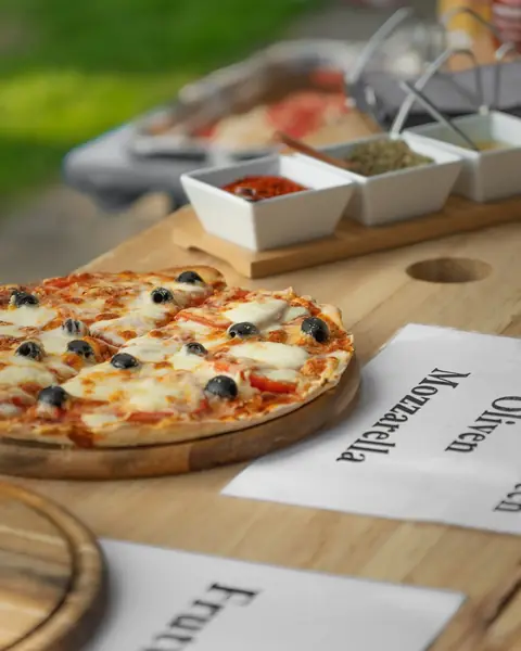 Pizza mit Oliven und Mozzarella, daneben die Sortenschilder