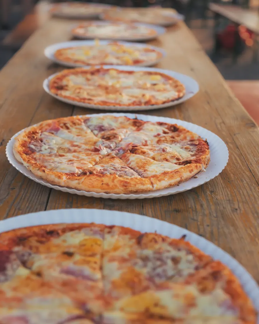 Eine Reihe frisch gebackener Pizzen auf dem Holztisch